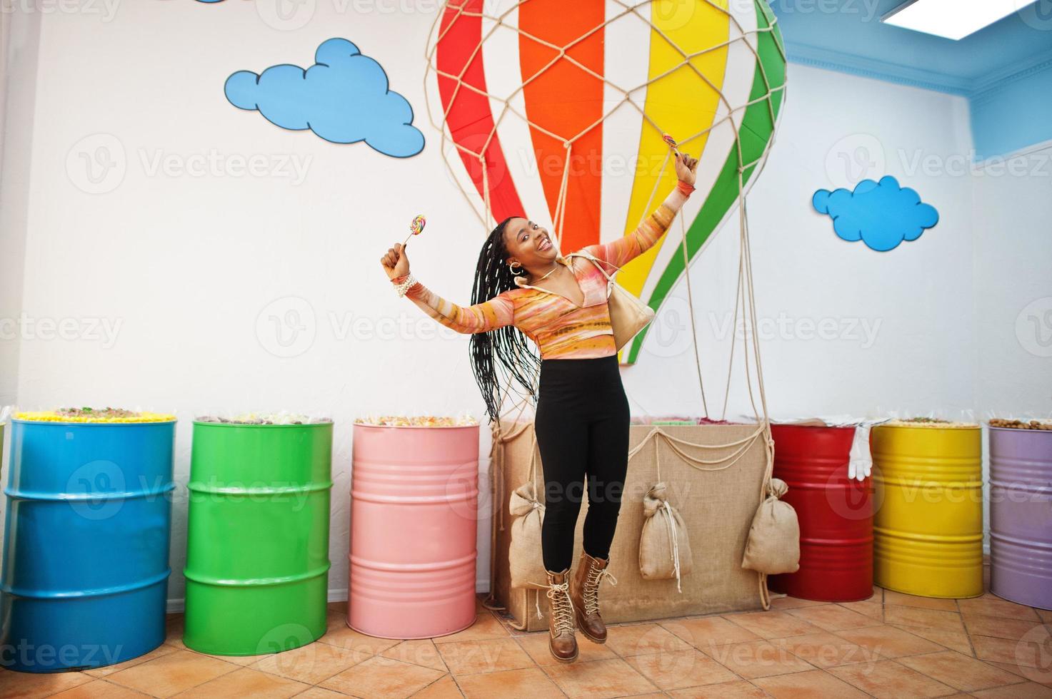 dame afro-américaine du millénaire au magasin de bonbons avec des lolipops. photo