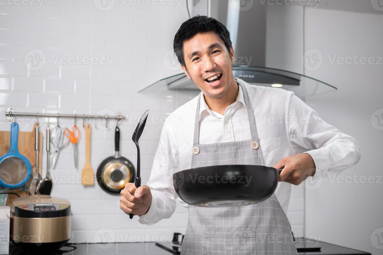 un chef asiatique a fait frire des œufs sur une poêle à de la nourriture thaïlandaise dans une cuisine sur une cuisinière à gaz l'huile dans une poêle bouillante. des œufs et du porc cuits. avant de servir à une famille heureuse pour manger ensemble à la maison photo