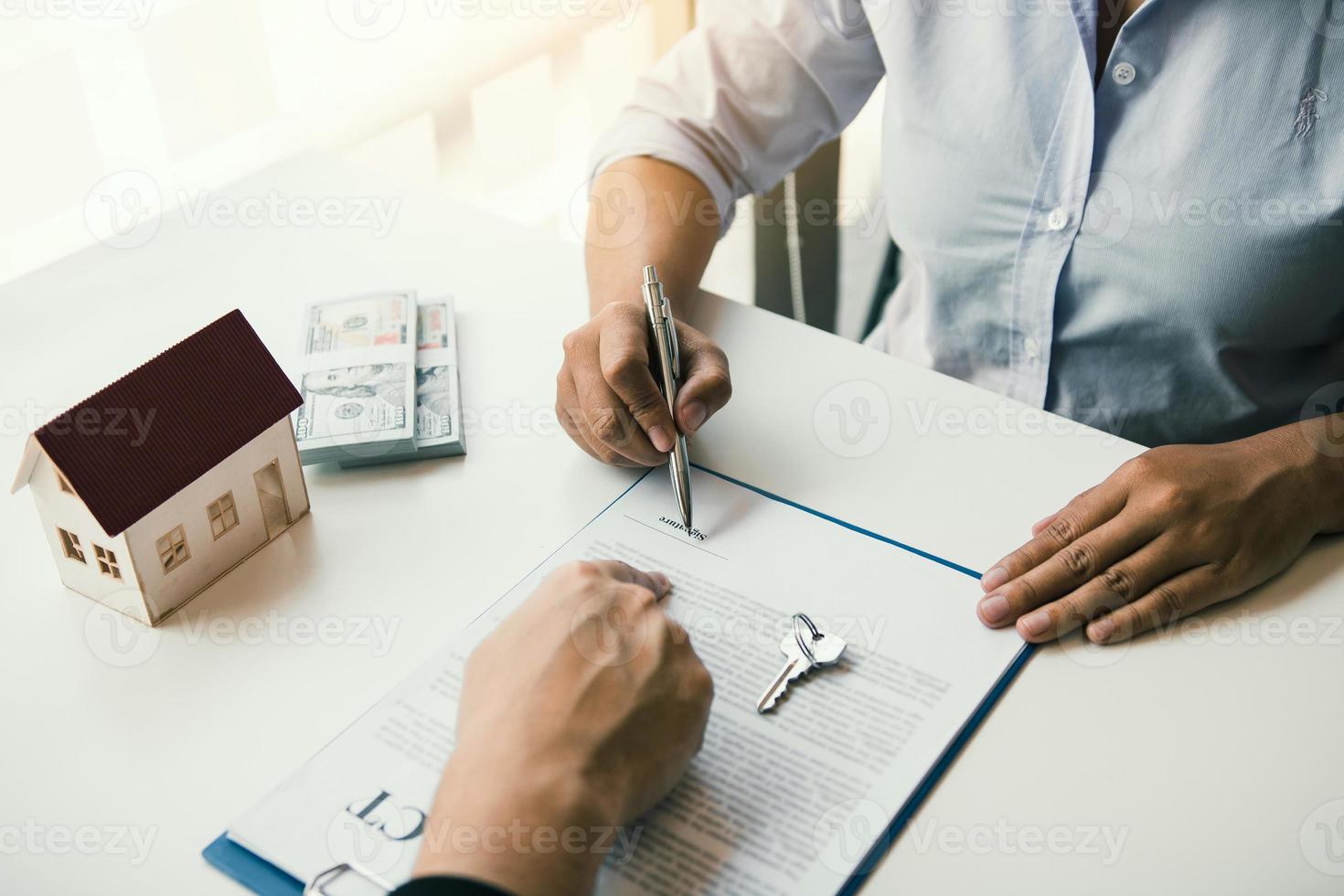 les courtiers d'assurance pointent vers la signature du contrat d'assurance et expliquent aux clients au bureau. photo