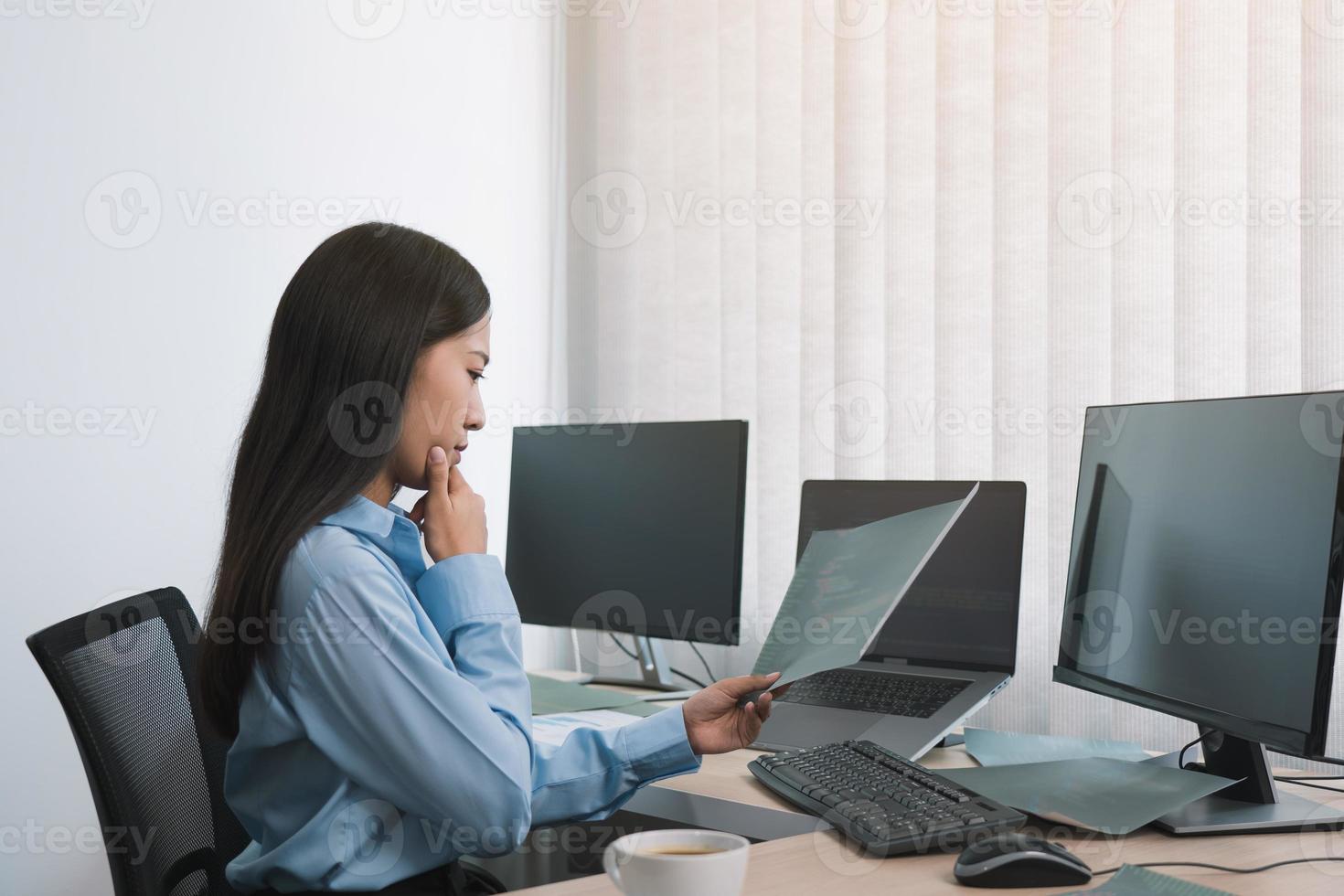 stresser une femme asiatique tout en codant un programmeur de données sur un ordinateur de bureau tout en travaillant sur des codes informatiques au bureau. photo