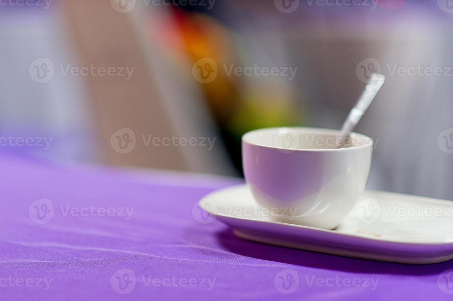 une tasse à café blanche est placée sur une table violette. concept de café avec espace de copie photo