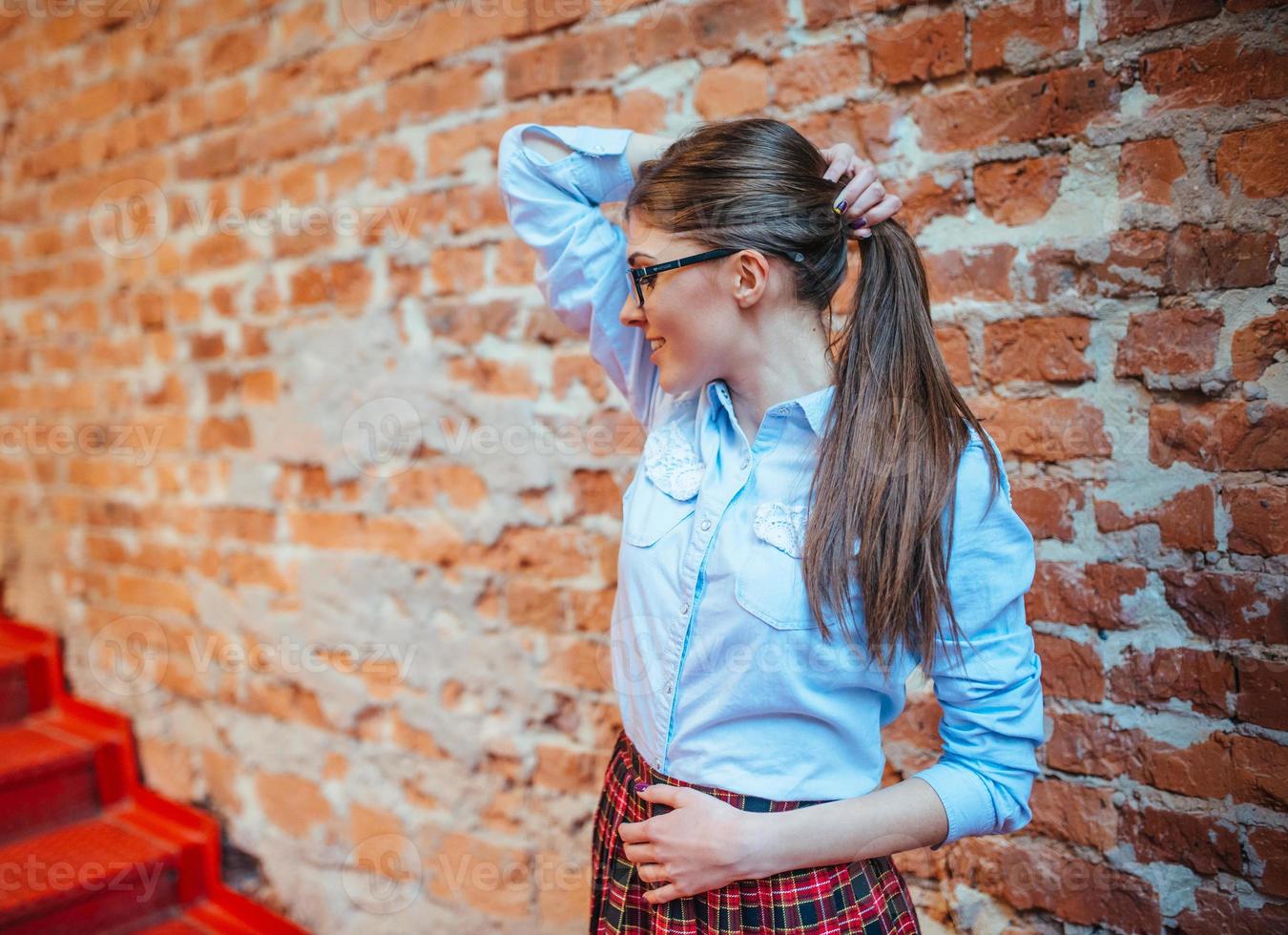 belle jeune femme se tient près du vieux mur de briques. style jeunesse photo