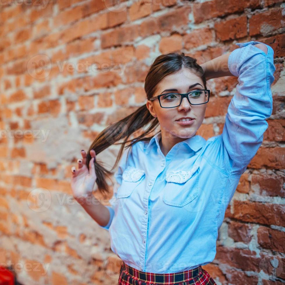 belle jeune femme se tient près du vieux mur de briques. style jeunesse photo