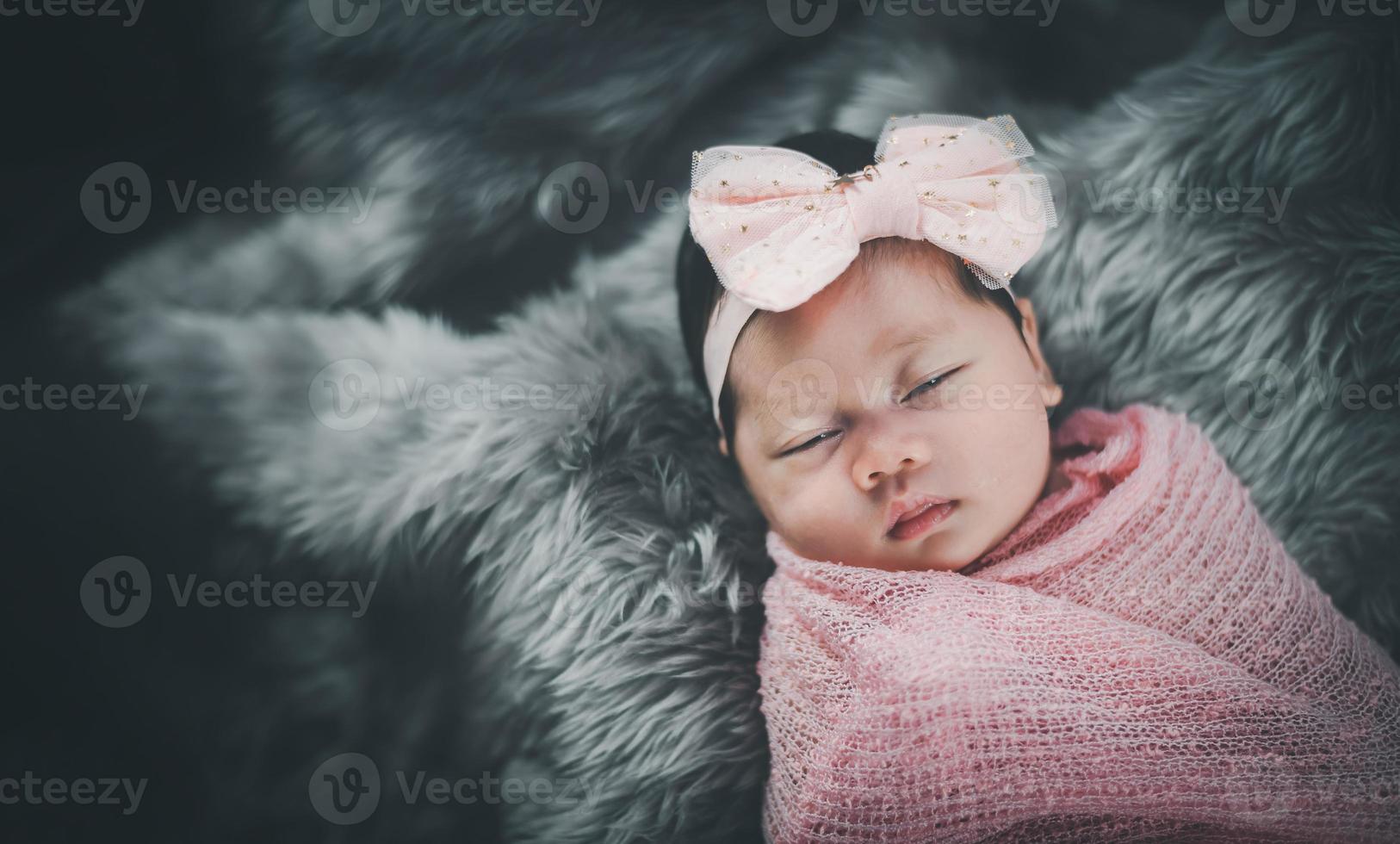 petite fille asiatique dormant sur le lit. portrait bébé fille studio éclairage sur lit de fourrure. concept de famille bébé photo