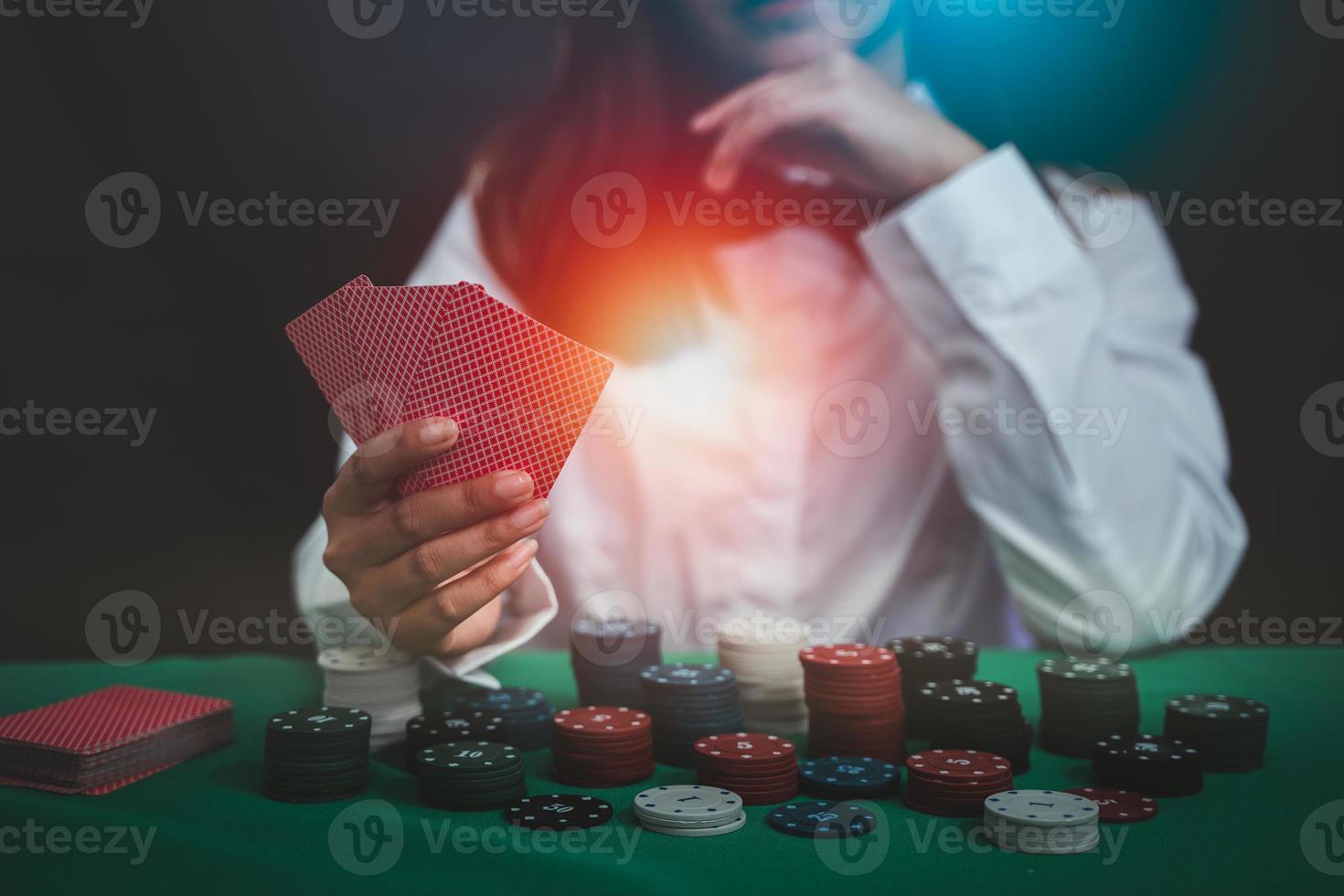 une femme asiatique croupier ou croupier mélange des cartes de poker dans un casino sur le fond d'une table, comme une femme tenant deux cartes à jouer. casino, poker, concept de jeu de poker photo