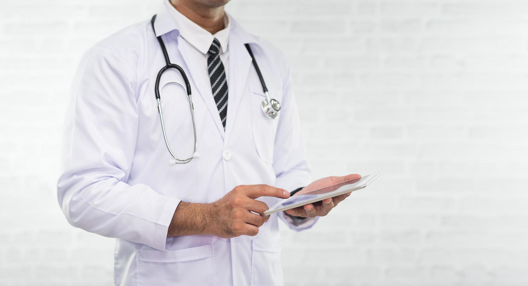 médecin travaillant sur une tablette numérique isolée sur fond blanc. médecin en blouse médicale à l'aide de tablette numérique. concept d'hôpital de médecin de santé. photo
