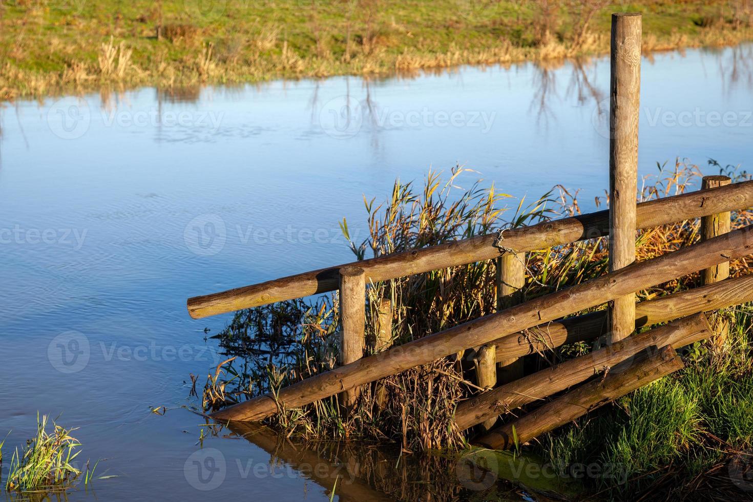 Clôture en bois ensoleillée par des terres inondées près d'Ely photo