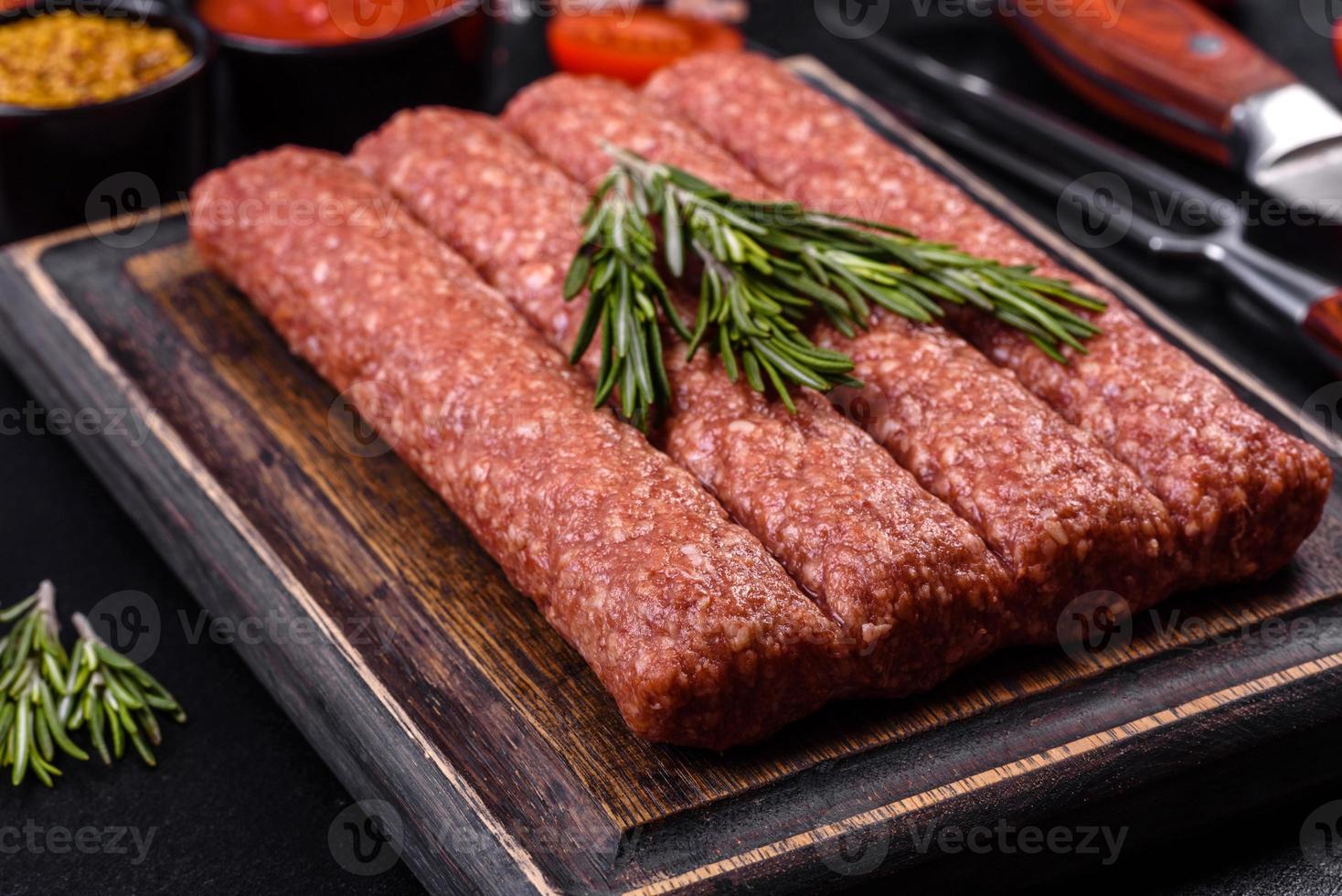 hachis cru frais pour kebab grillé avec épices et herbes sur fond de béton foncé photo
