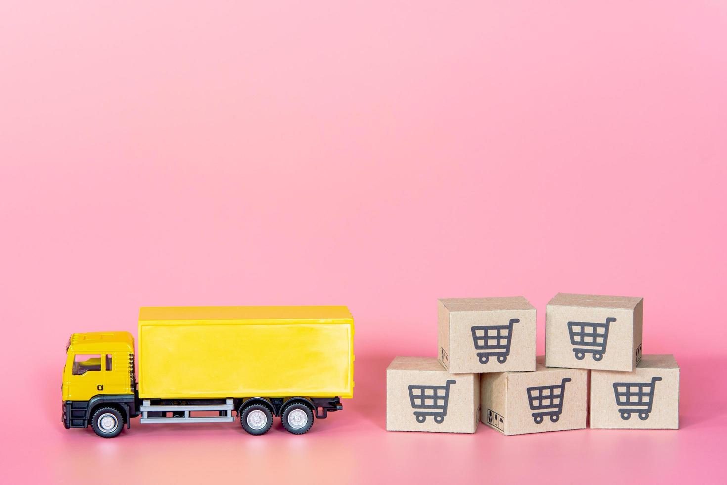 logistique et service de livraison - camion de fret et cartons en papier ou colis avec un logo de panier sur fond rose. service d'achat sur le web en ligne et propose la livraison à domicile. photo