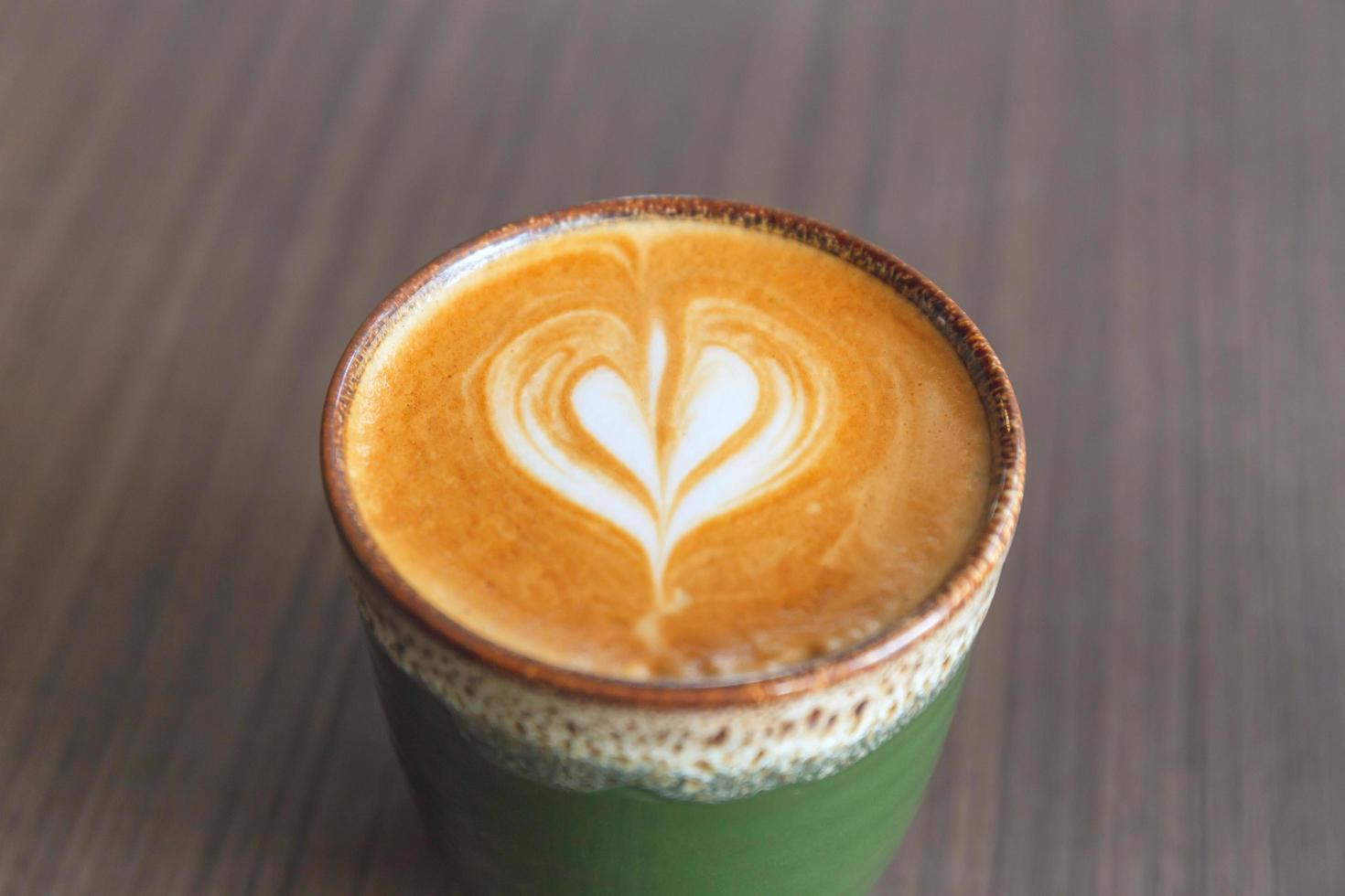 mise au point sélective de café latte art chaud dans une tasse en céramique sur fond de table en bois flou photo