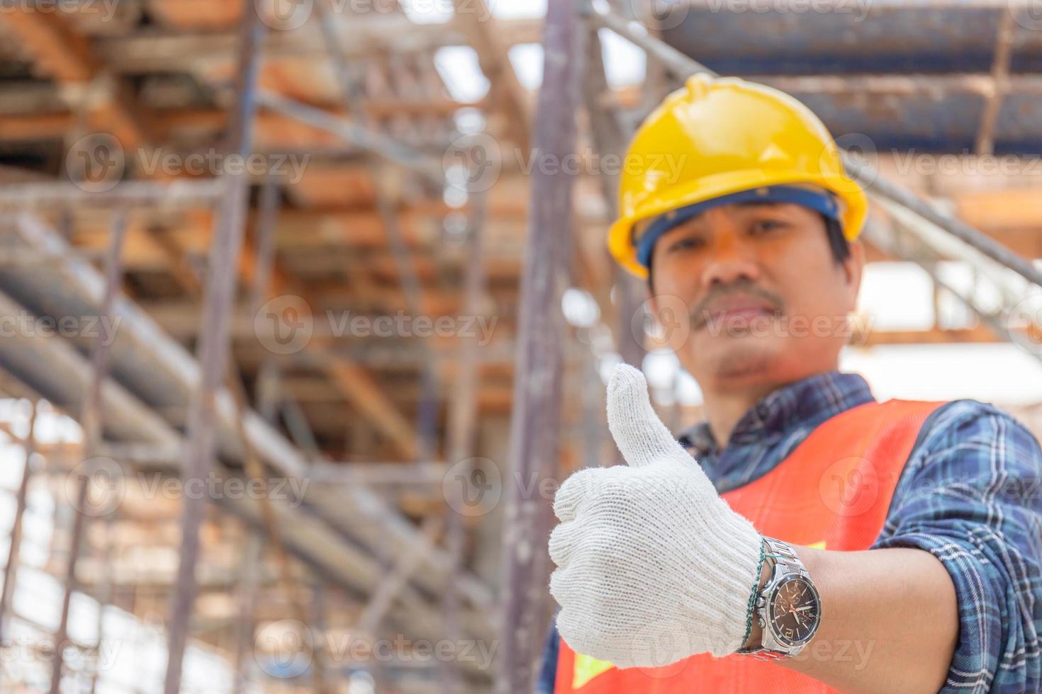 main d'homme ouvrier ingénieur abandonnant le pouce vers le haut sur un chantier de construction flou, concept réussi photo