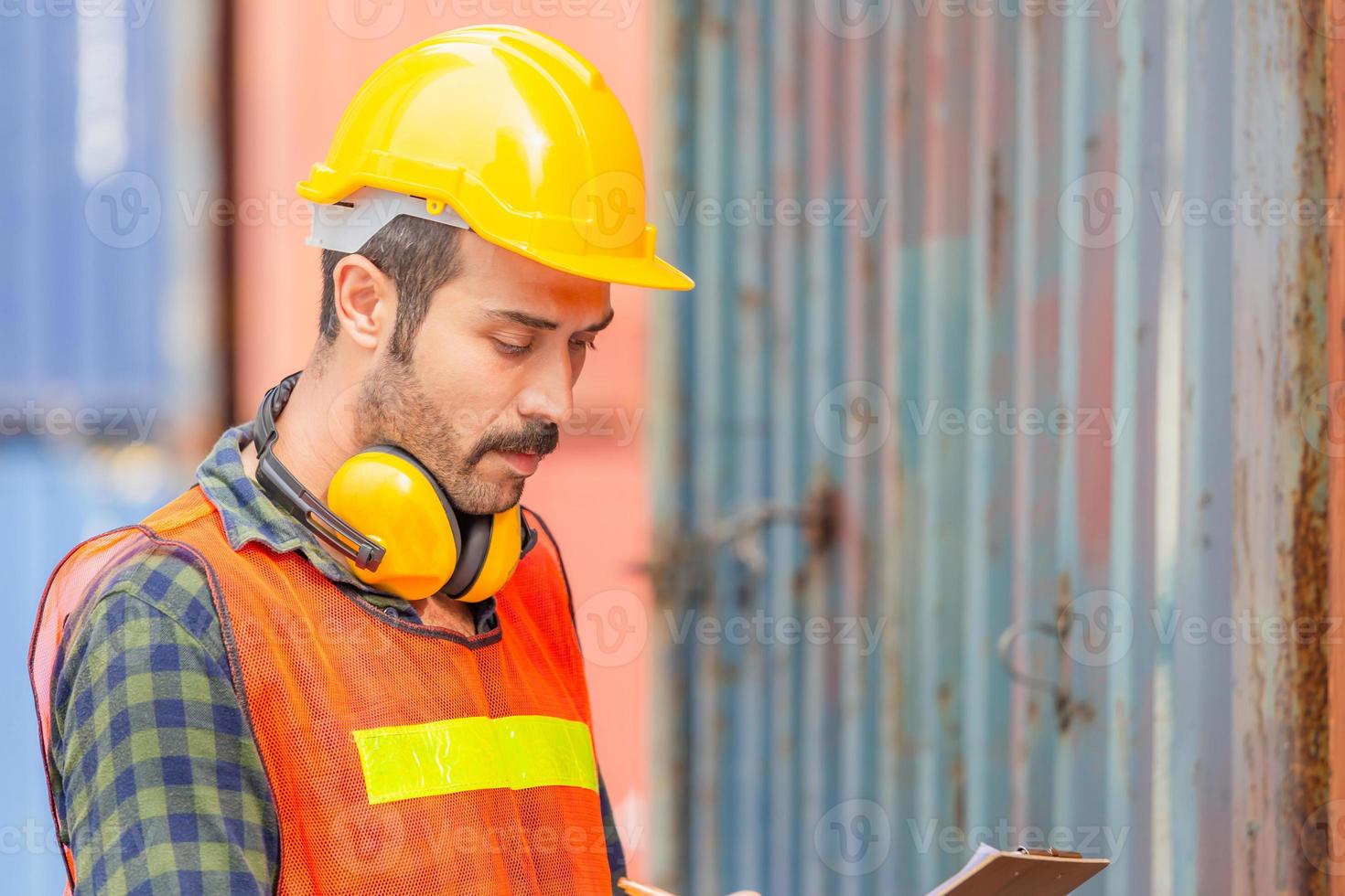 portrait d'un ouvrier d'usine portant un casque et un gilet de sécurité, un ingénieur avec un fond de boîte de conteneurs à la cargaison photo