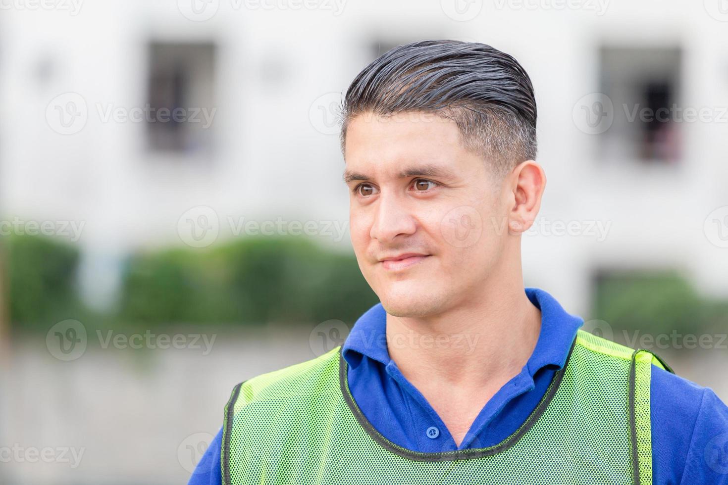 portrait d'un beau travailleur professionnel portant un gilet de sécurité regardant au loin. photo