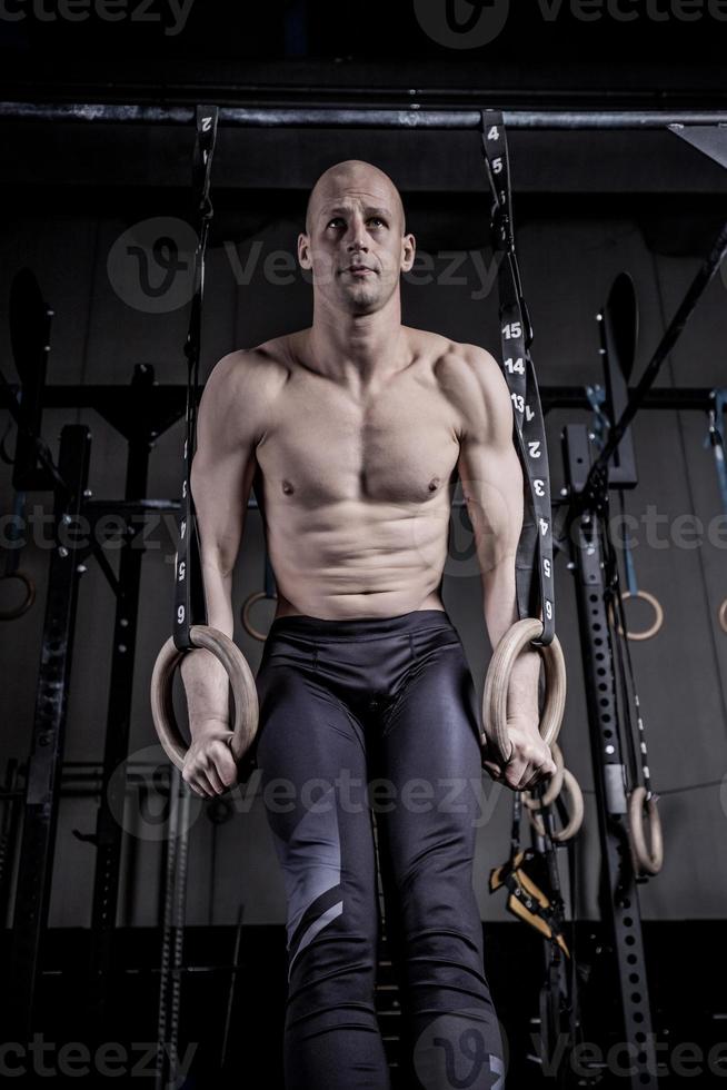 athlète faisant des pompes avec des anneaux au gymnase. photo