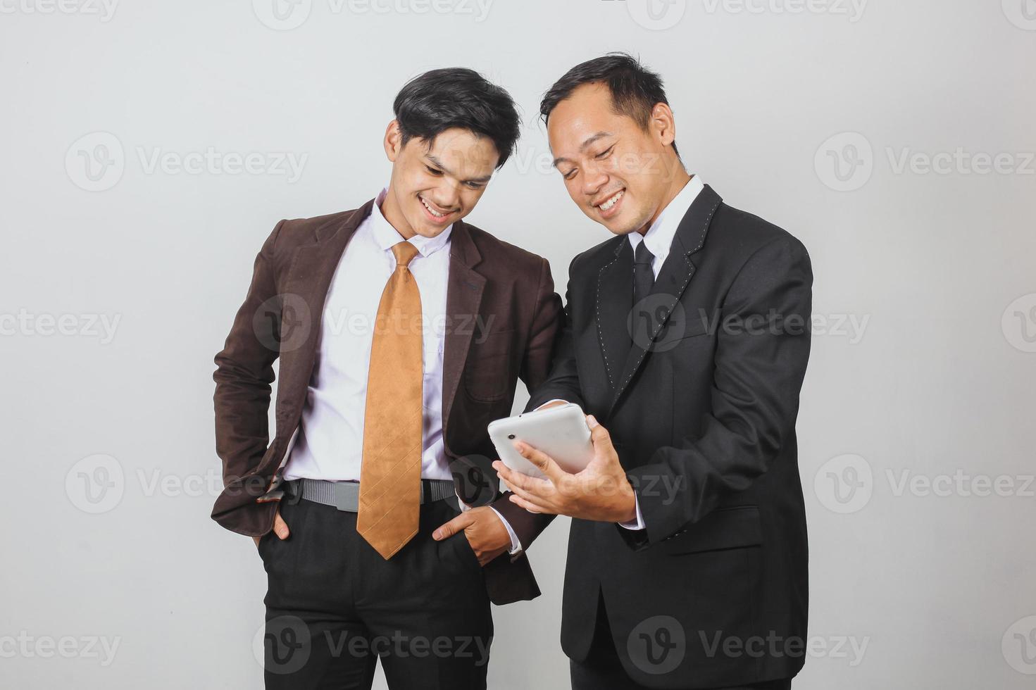 deux hommes d'affaires asiatiques en costume discutant à l'aide d'un téléphone intelligent photo