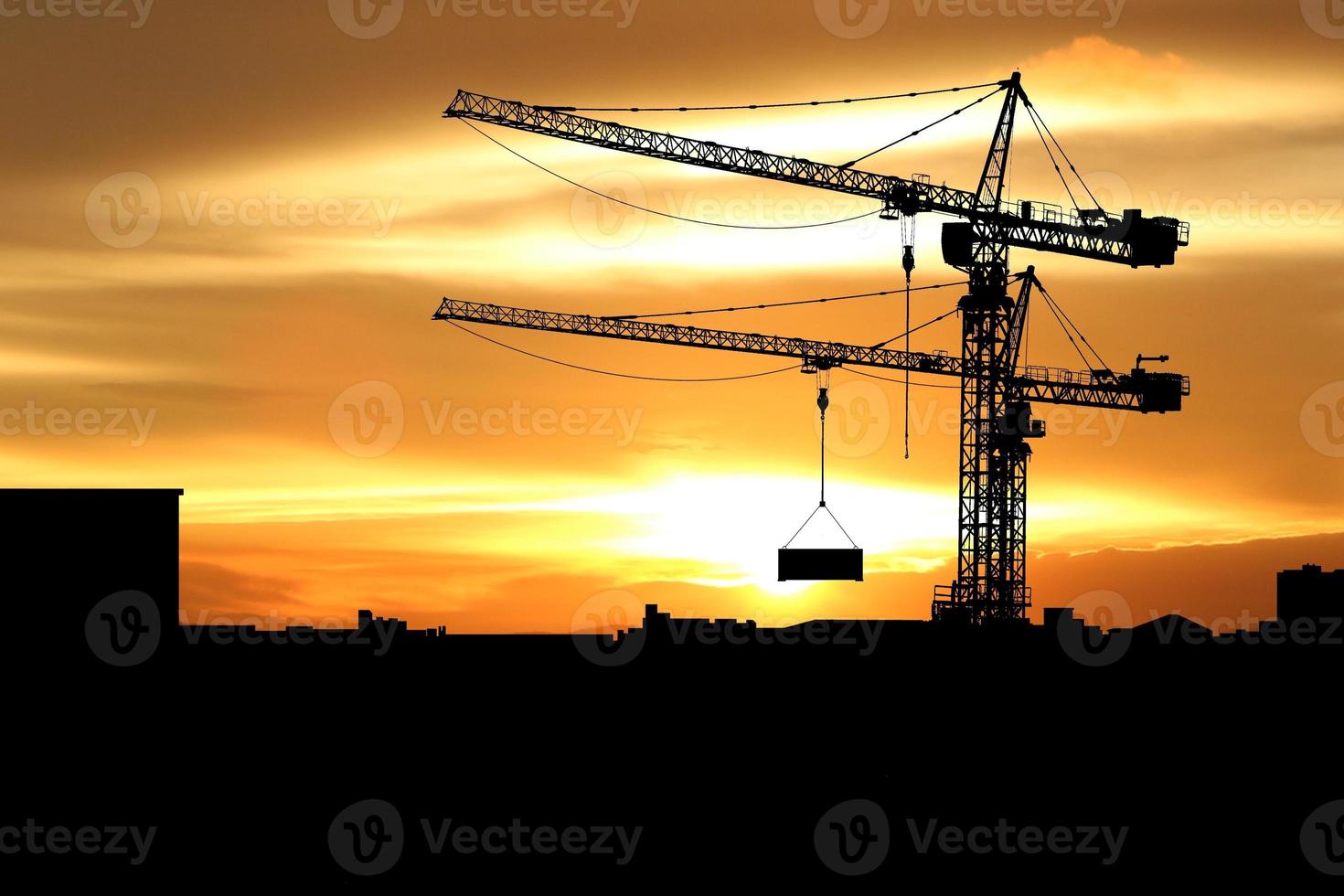 silhouette de grue à tour sur un chantier de construction sur fond de coucher de soleil. photo