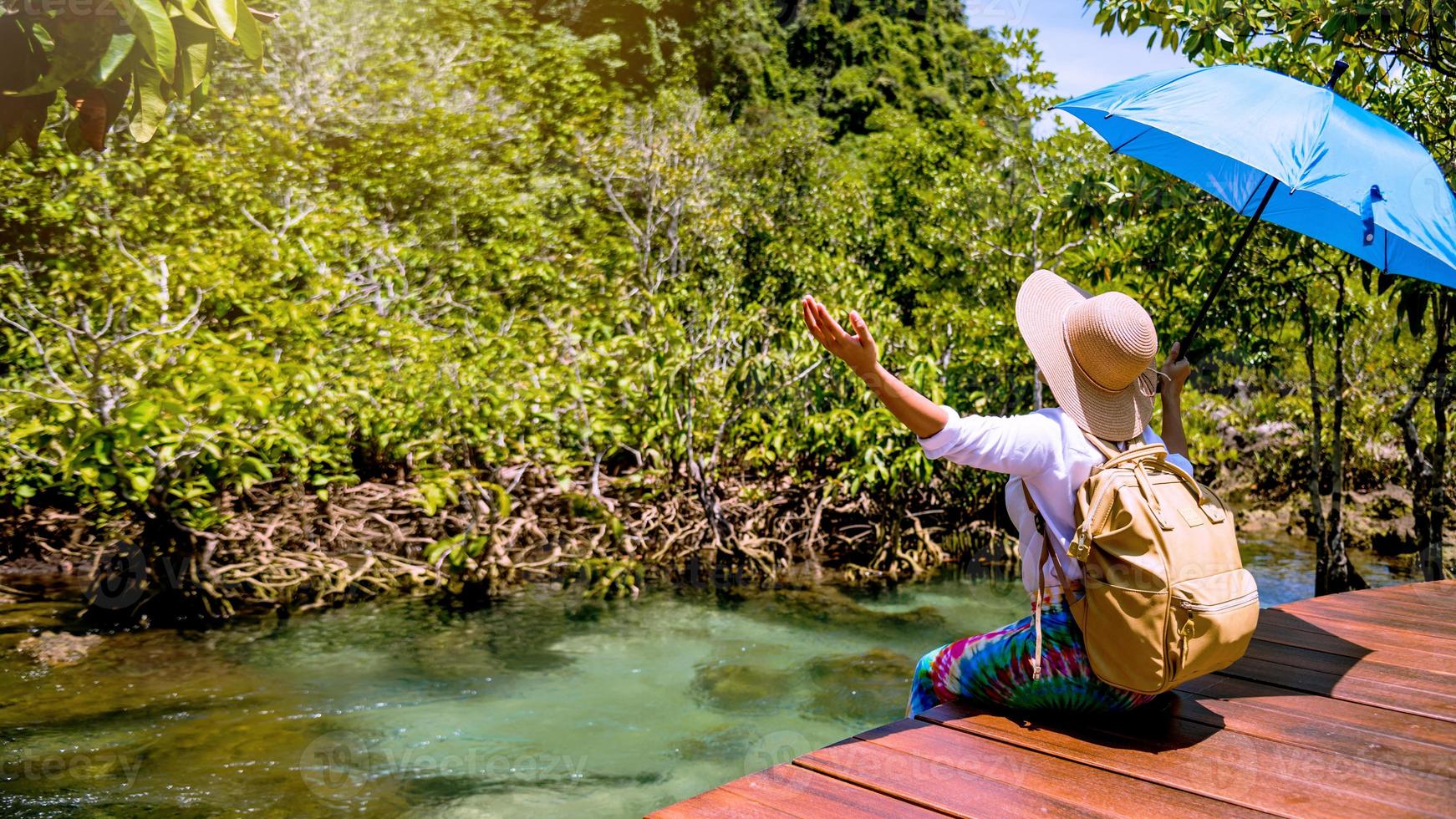 les femmes asiatiques voyagent se détendent, voyagent dans la nature pendant les vacances. des femmes qui aiment s'asseoir et regarder la nature de la forêt du lac à tha pom-klong-song-nam à krabi. été, voyage en Thaïlande. photo