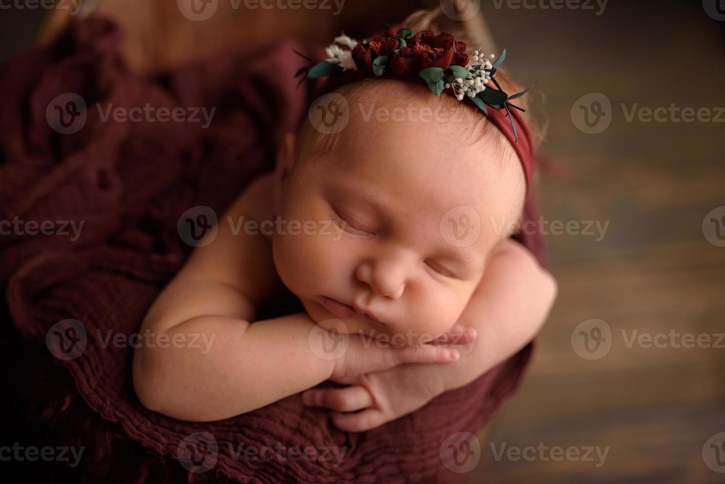 jolie fille nouveau-née dormant dans une baignoire sur un fond en bois. photo