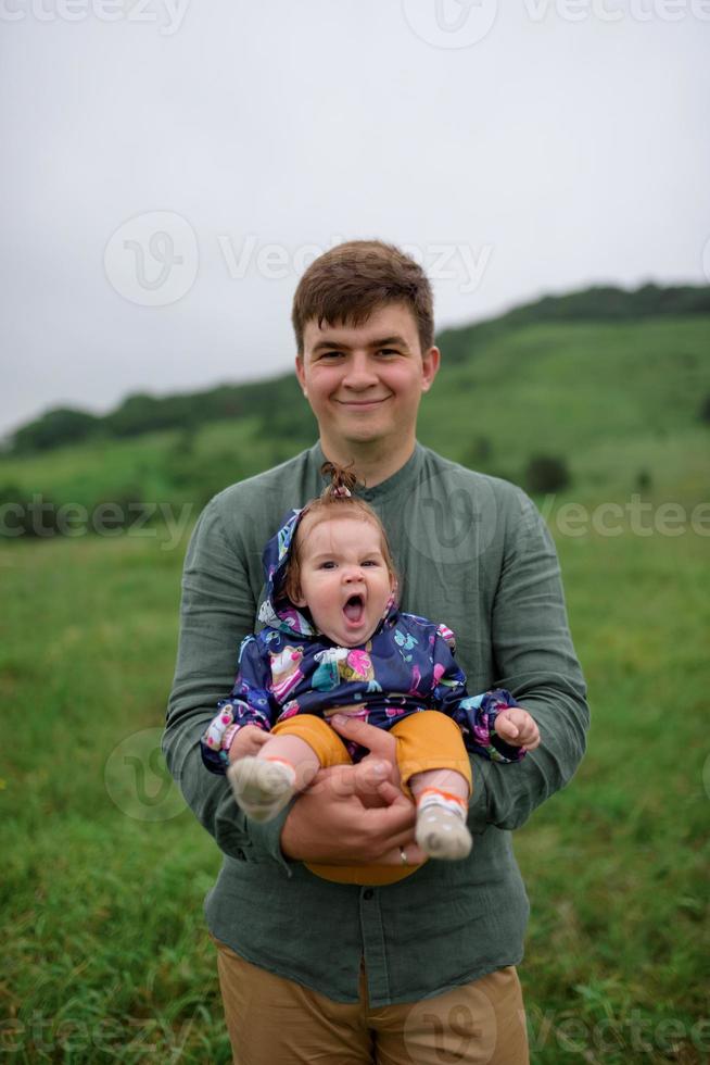 maman, papa et fille. les parents tiennent le bébé par les mains et vont vers la caméra. photo