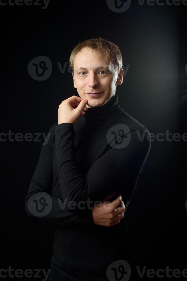 portrait d'un homme beau et déterminé portant une chemise noire, fond noir. photo