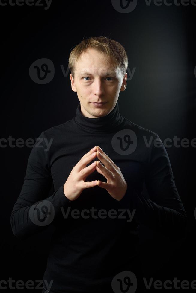 portrait d'un homme beau et déterminé portant une chemise noire, fond noir. photo