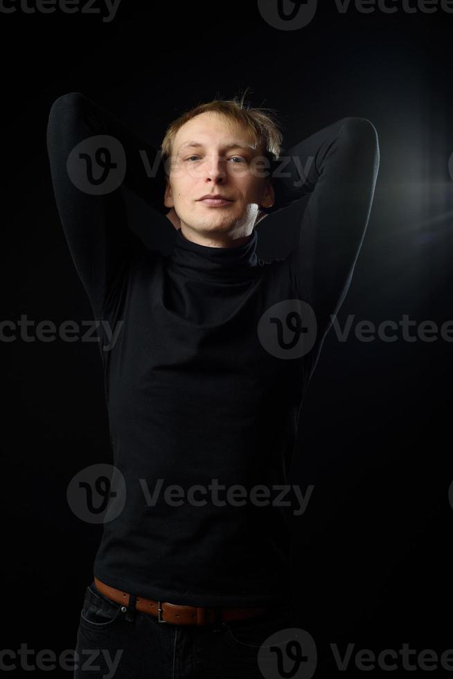 portrait d'un homme beau et déterminé portant une chemise noire, fond noir. photo