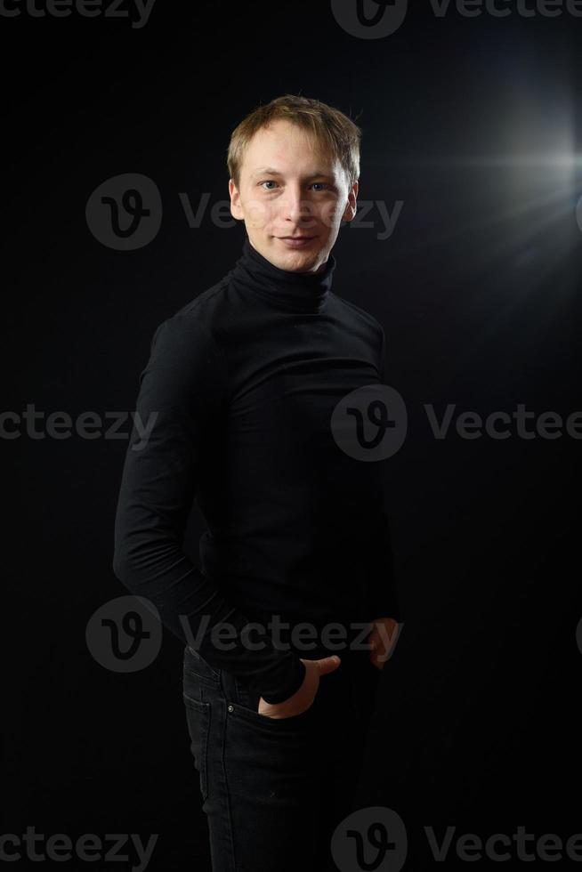 portrait d'un homme beau et déterminé portant une chemise noire, fond noir. photo