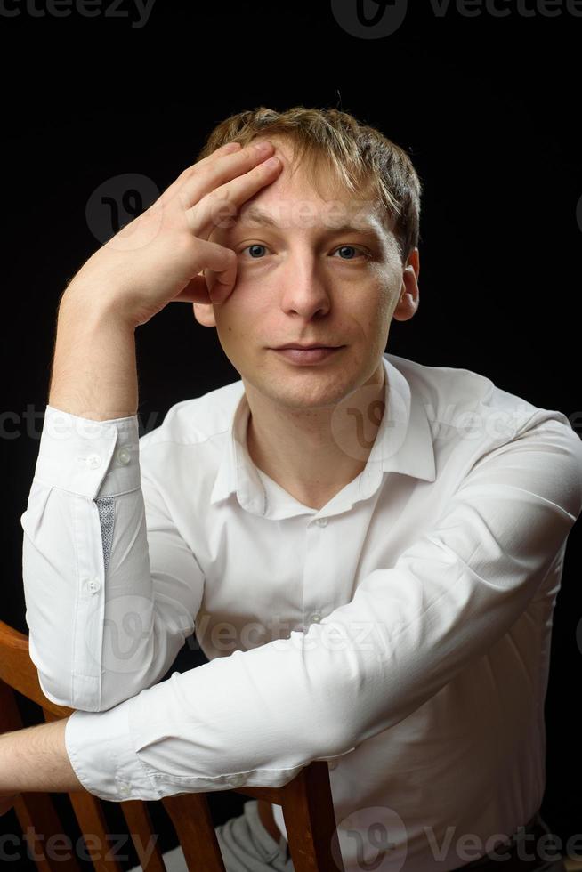 portrait en gros plan d'un jeune homme en chemise blanche et cravate noire, souriant en regardant la caméra, sur fond de studio uni photo