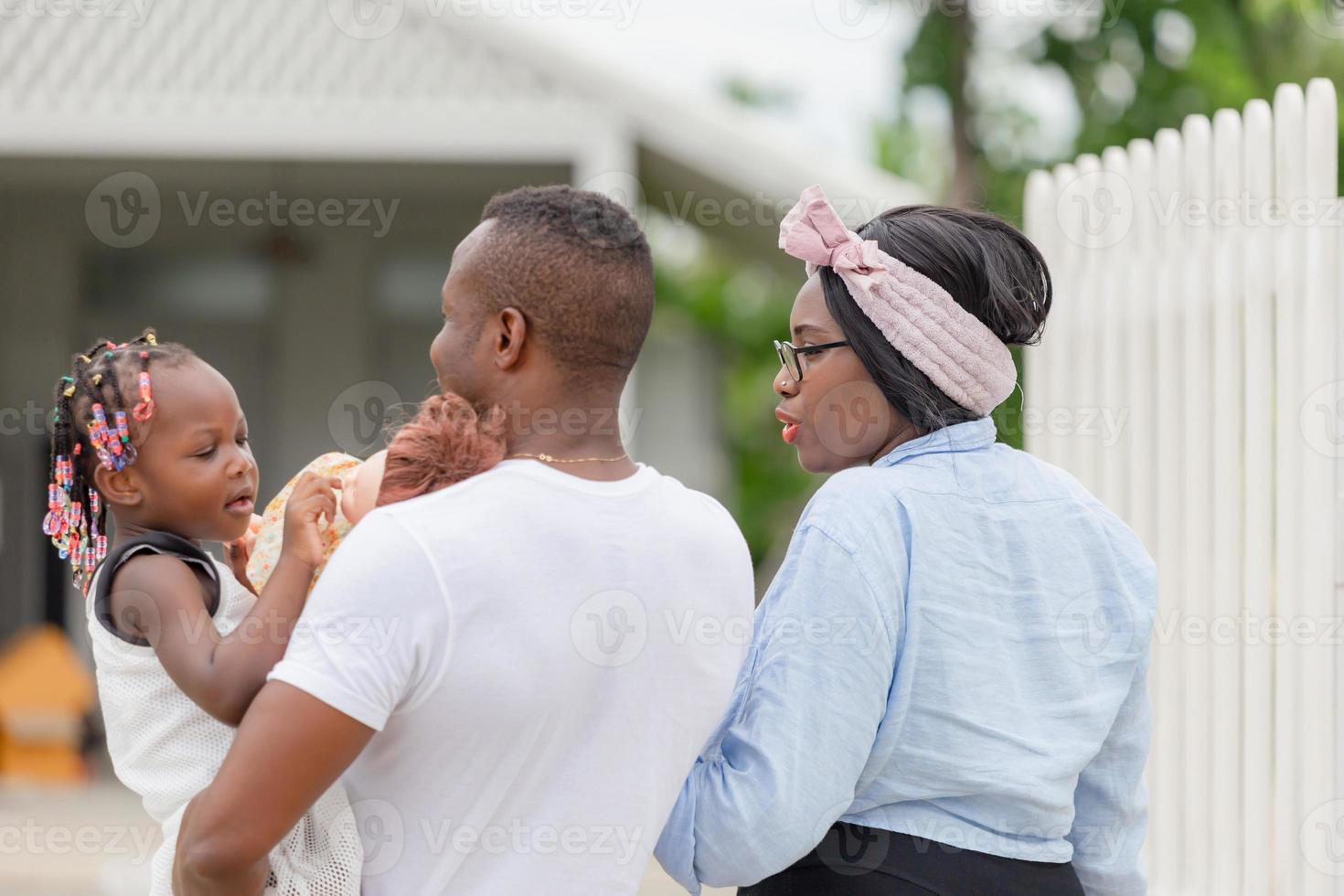 bonheur famille afro-américaine marchant vers une nouvelle maison, père mère et fille devant leur nouvelle maison photo
