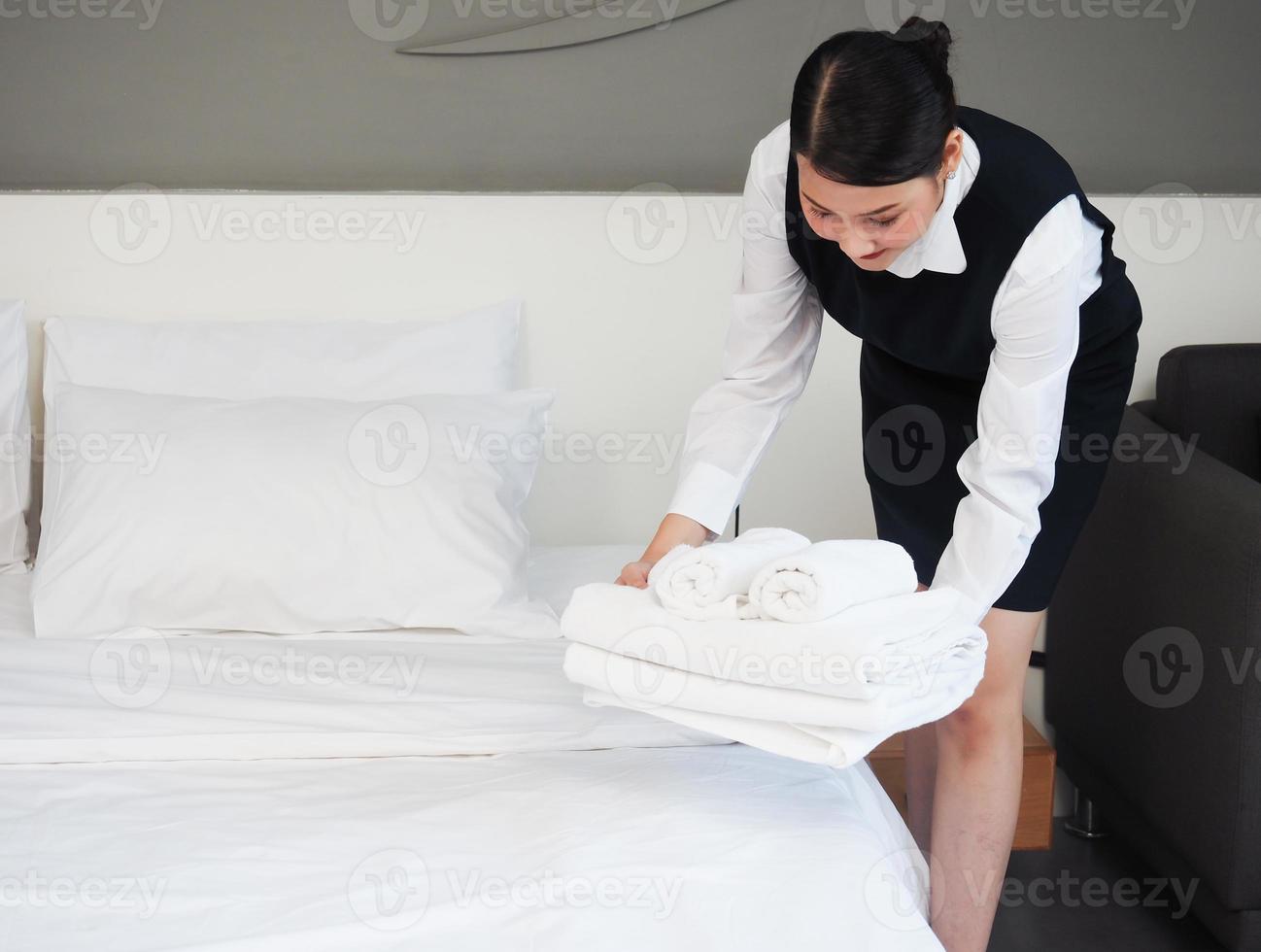 une femme de ménage installant l'oreiller blanc sur le drap de la chambre d'hôtel. nettoyage dans la chambre d'hôtel. le concept de l'hôtellerie. photo