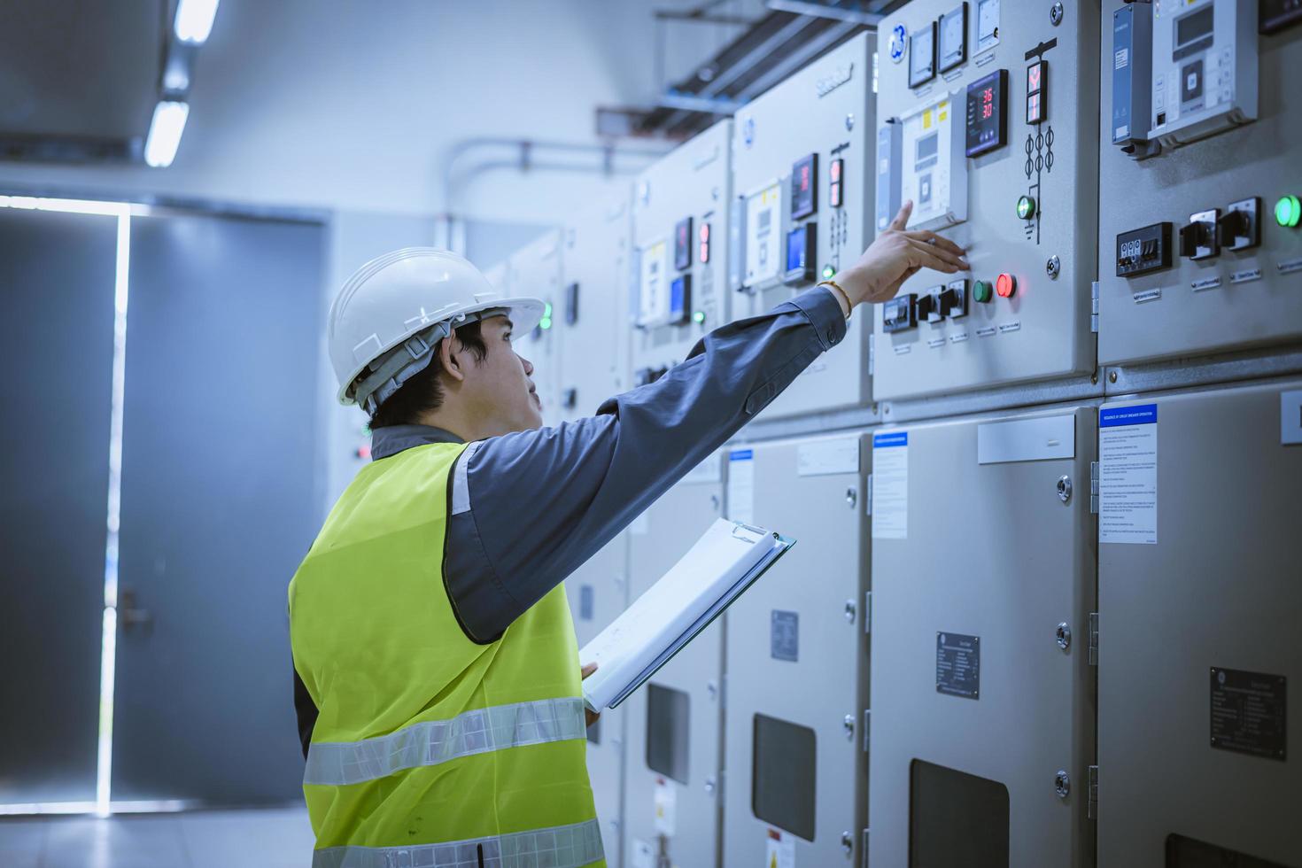 ingénieur vérifiant et inspectant au panneau mdb. ils travaillent avec un tableau électrique pour vérifier la plage de tension fonctionnant dans l'usine de tableaux de distribution principaux. photo