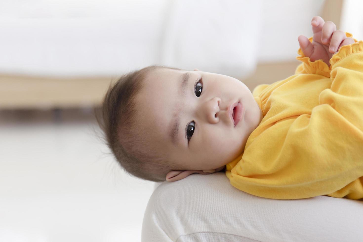 un bébé asiatique est allongé sur les genoux de sa mère. photo