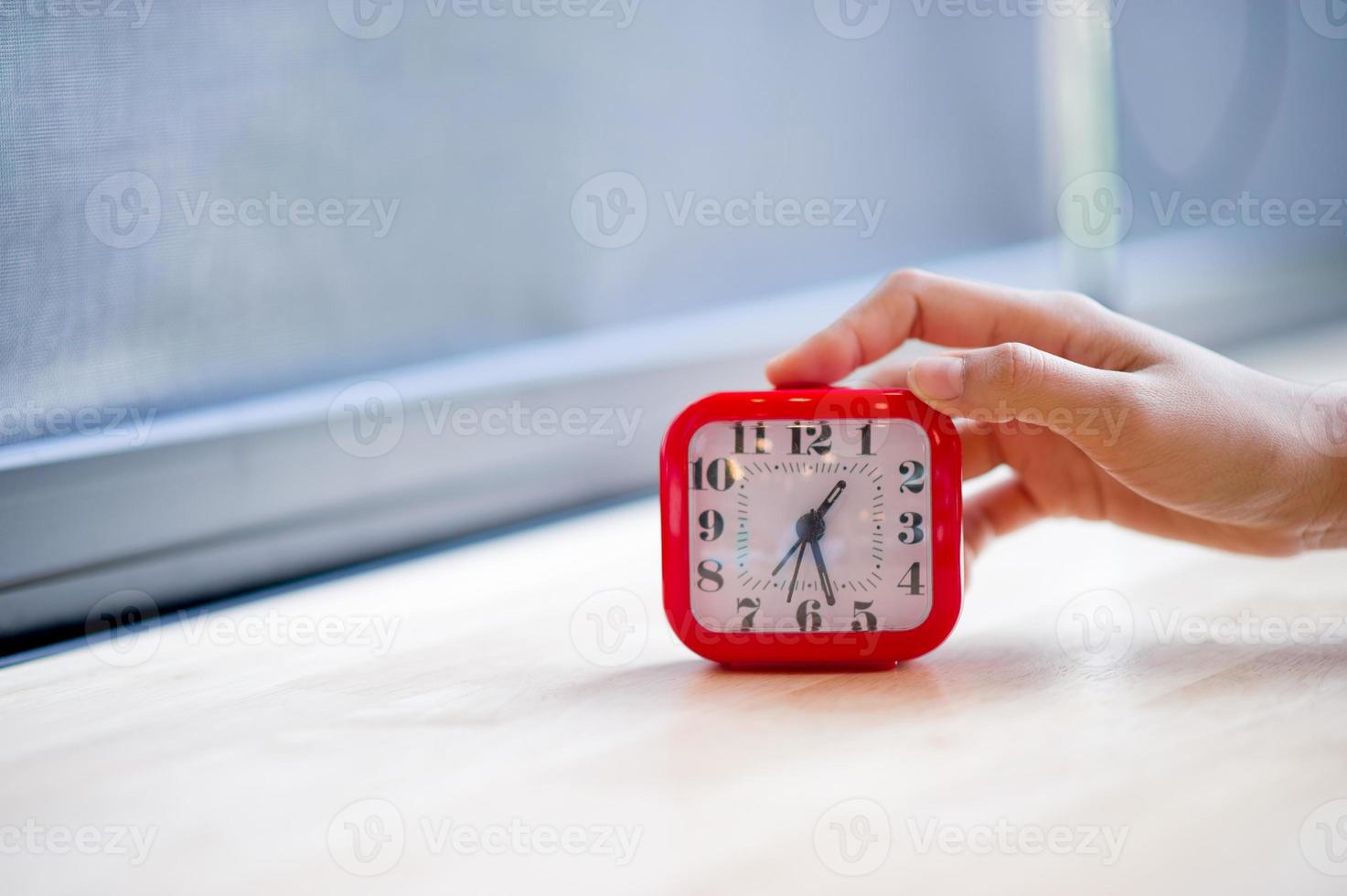 main et réveil rouge qui montre l'alarme du tout tous les matins, le concept de ponctualité photo