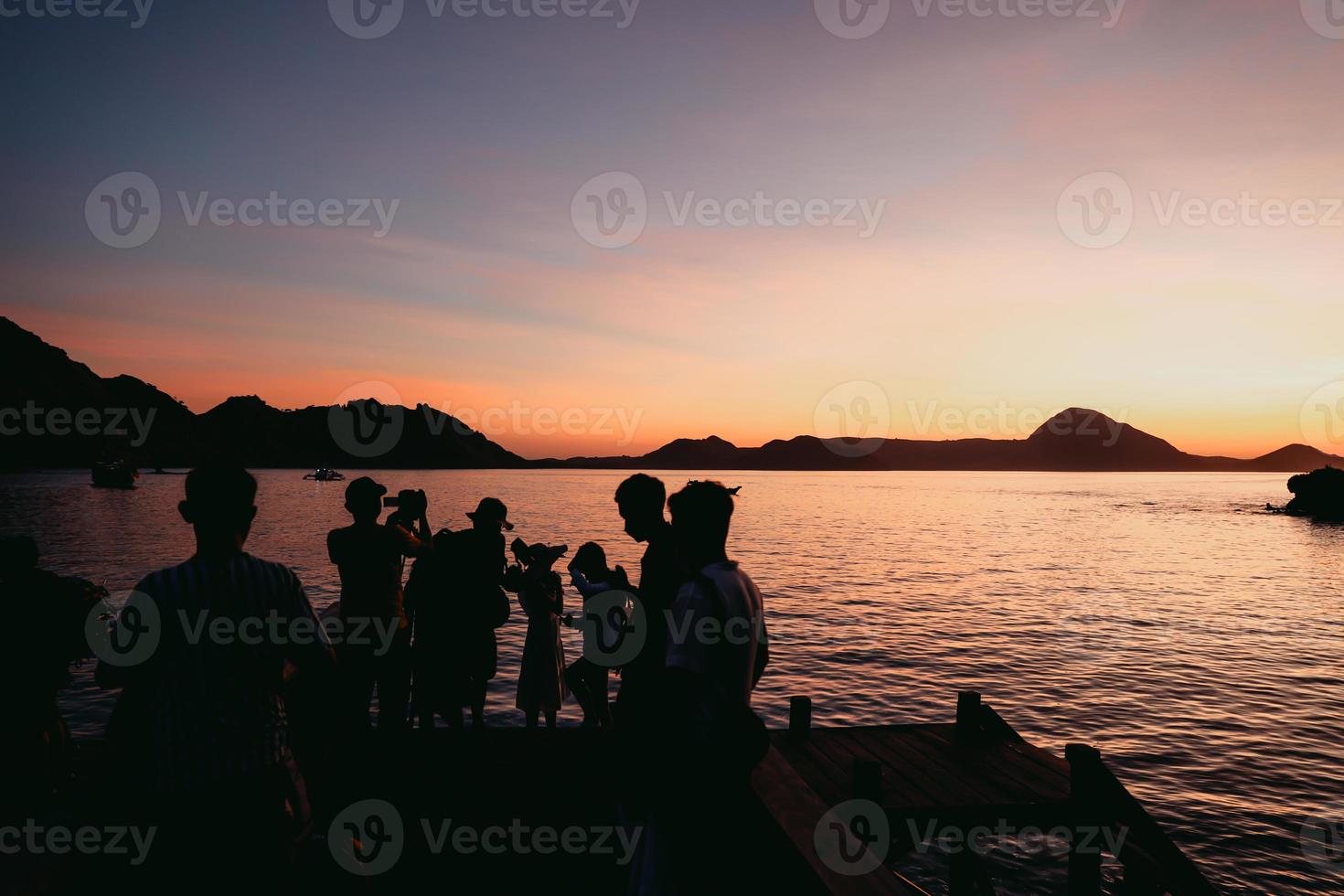 silhouette noire de touristes se rassemblant et faisant une séance photo avec la mer et les collines à labuan bajo