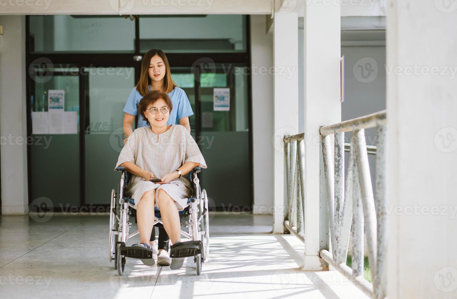 physiothérapeute souriant prenant soin de l'heureux patient âgé en fauteuil roulant photo