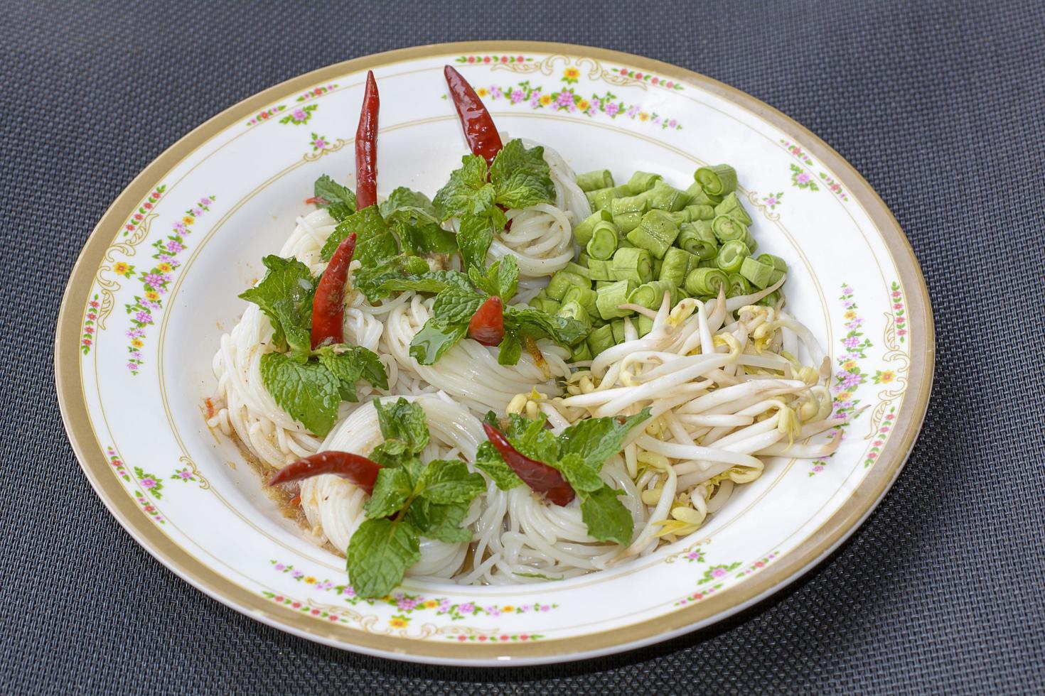 les nouilles de riz dans une sauce au curry de poisson avec des légumes ou des vermicelles thaïlandais mangés avec du curry sont des plats thaïlandais. le plat est une cuisine délicieuse et épicée. photo