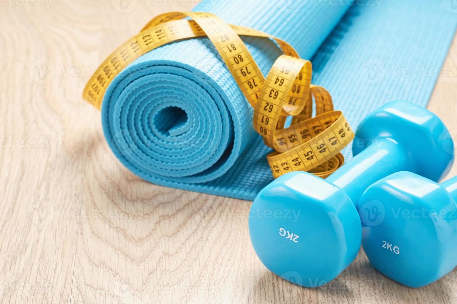 concept de remise en forme avec des haltères bleus, un tapis de fitness et un ruban à mesurer, espace de copie photo