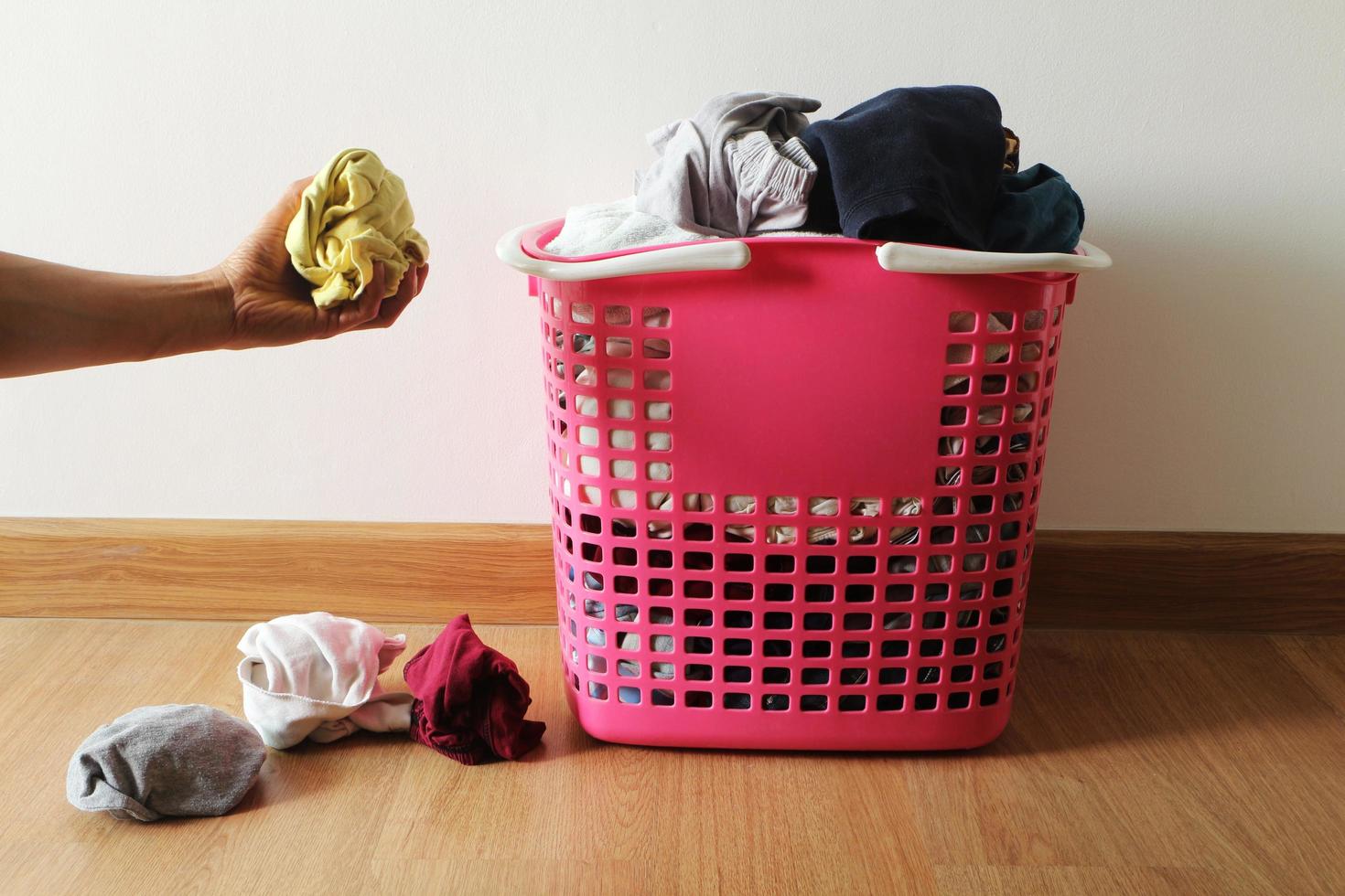 panier avec linge sale sur le parquet dans la chambre et la main d'un homme tenant un chiffon sale. photo