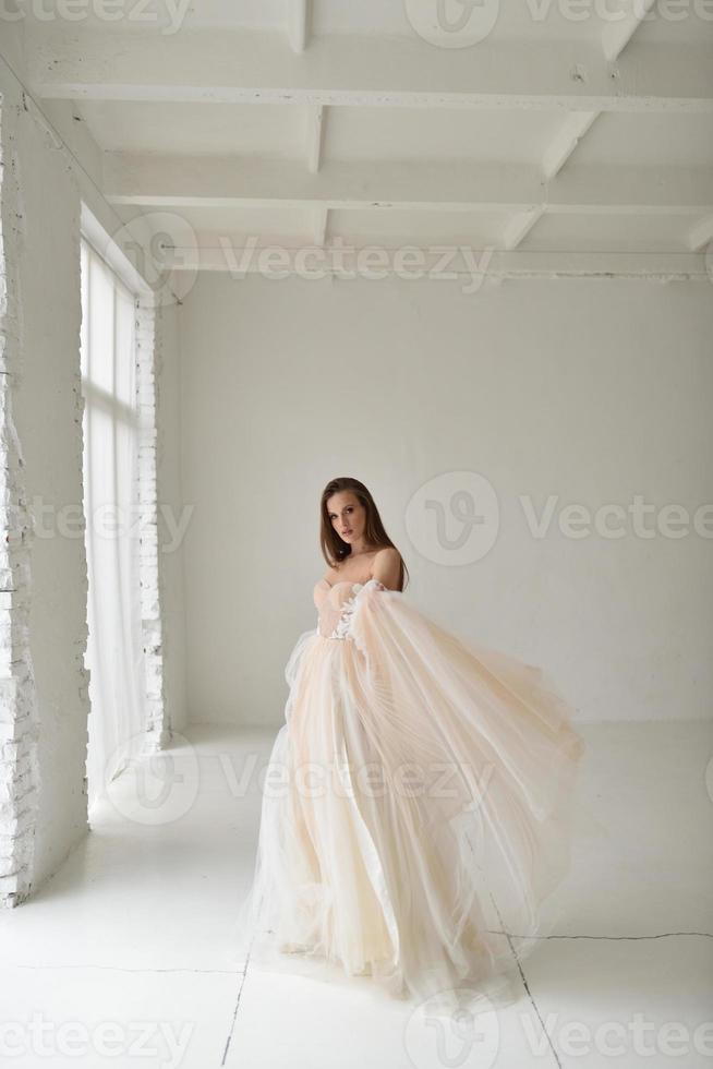 portrait d'une belle mariée en pleine croissance en studio sur fond blanc. la femme se tient dos et regarde dans le cadre. photo