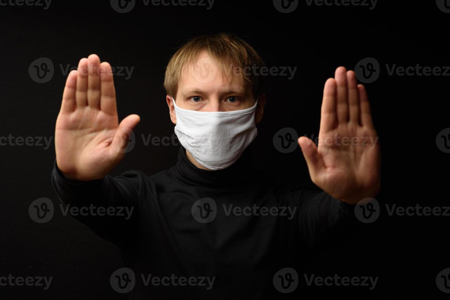 un homme d'âge moyen portant un masque médical montre un arrêt avec sa main. le concept de protection contre le coranavirus. photo