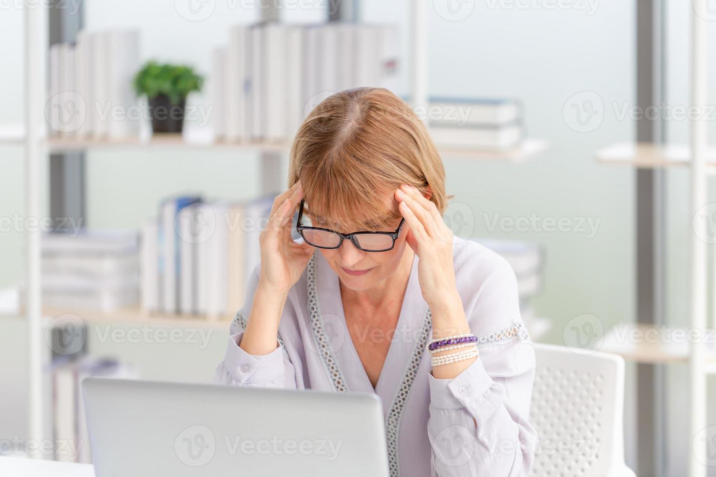 une femme mûre malsaine touche le front souffre de fortes migraines, une femme massant les tempes en gros plan, souffrant d'un fort mal de tête photo