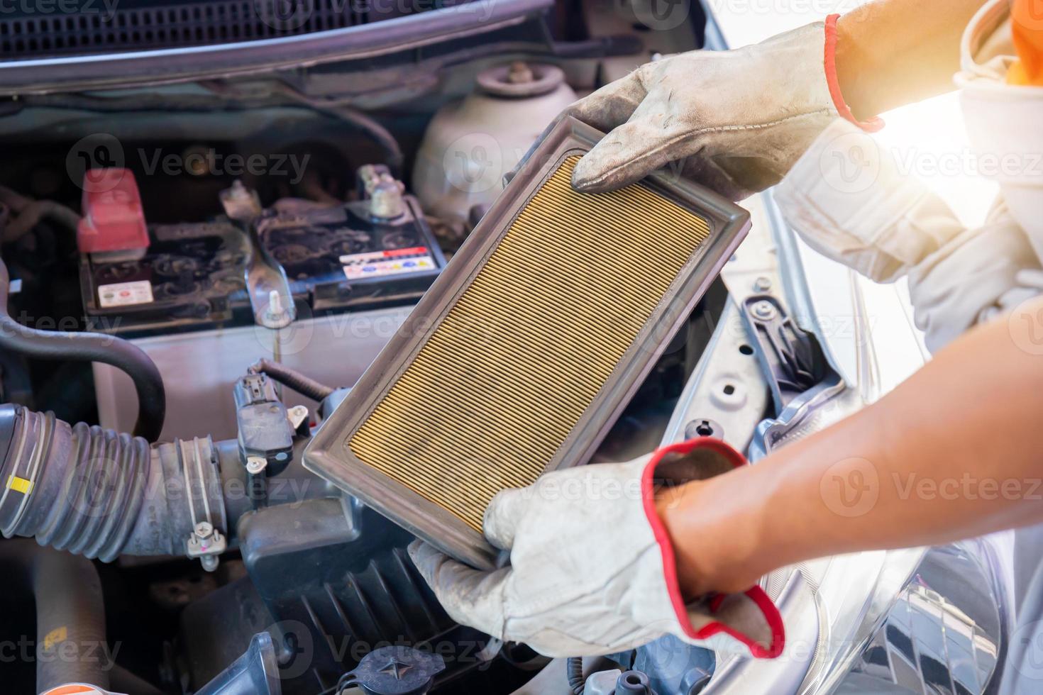 mécaniciens automobiles tenant le filtre à air de la voiture dans la salle des machines, technicien faisant la liste de contrôle pour réparer le moteur de la voiture dans le garage photo