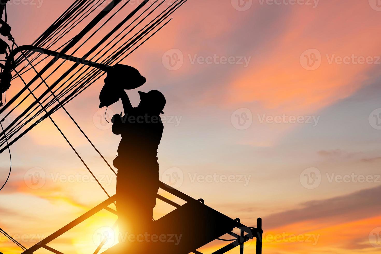 silhouette d'électricien vérifiant l'éclairage du lampadaire à led, technicien avec chemin de détourage et concepts de service de maintenance photo