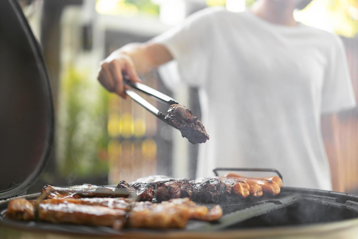 main de femme griller un barbecue en feu dans l'arrière-cour le jour photo