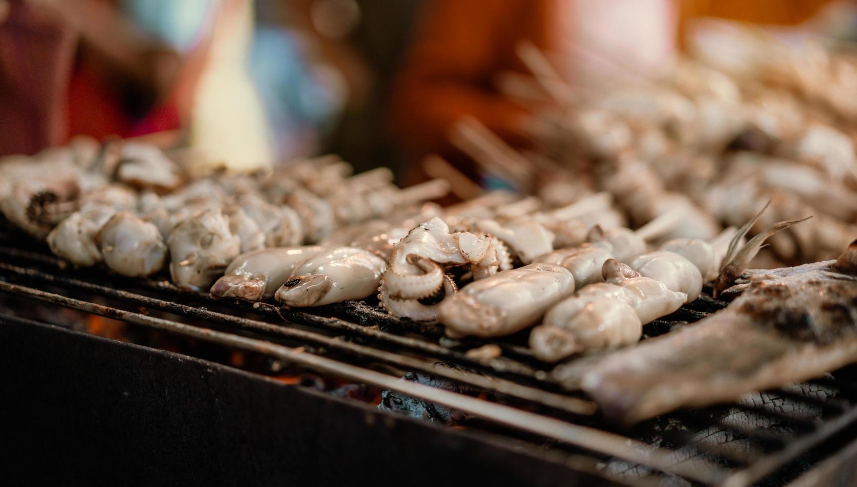 vendeur de brochettes de calamars grillés au charbon de bois. photo