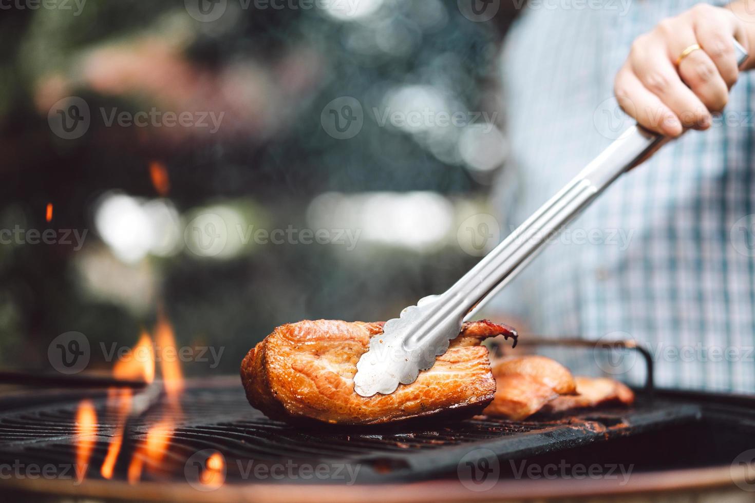 main d'homme grillant un barbecue en feu dans l'arrière-cour le jour photo