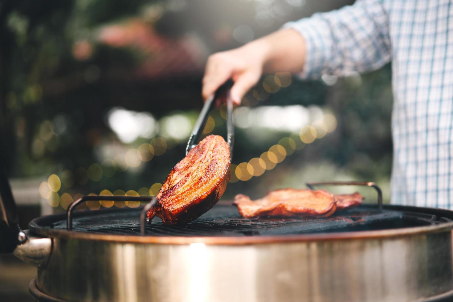 main d'homme grillant un barbecue en feu dans l'arrière-cour le jour photo