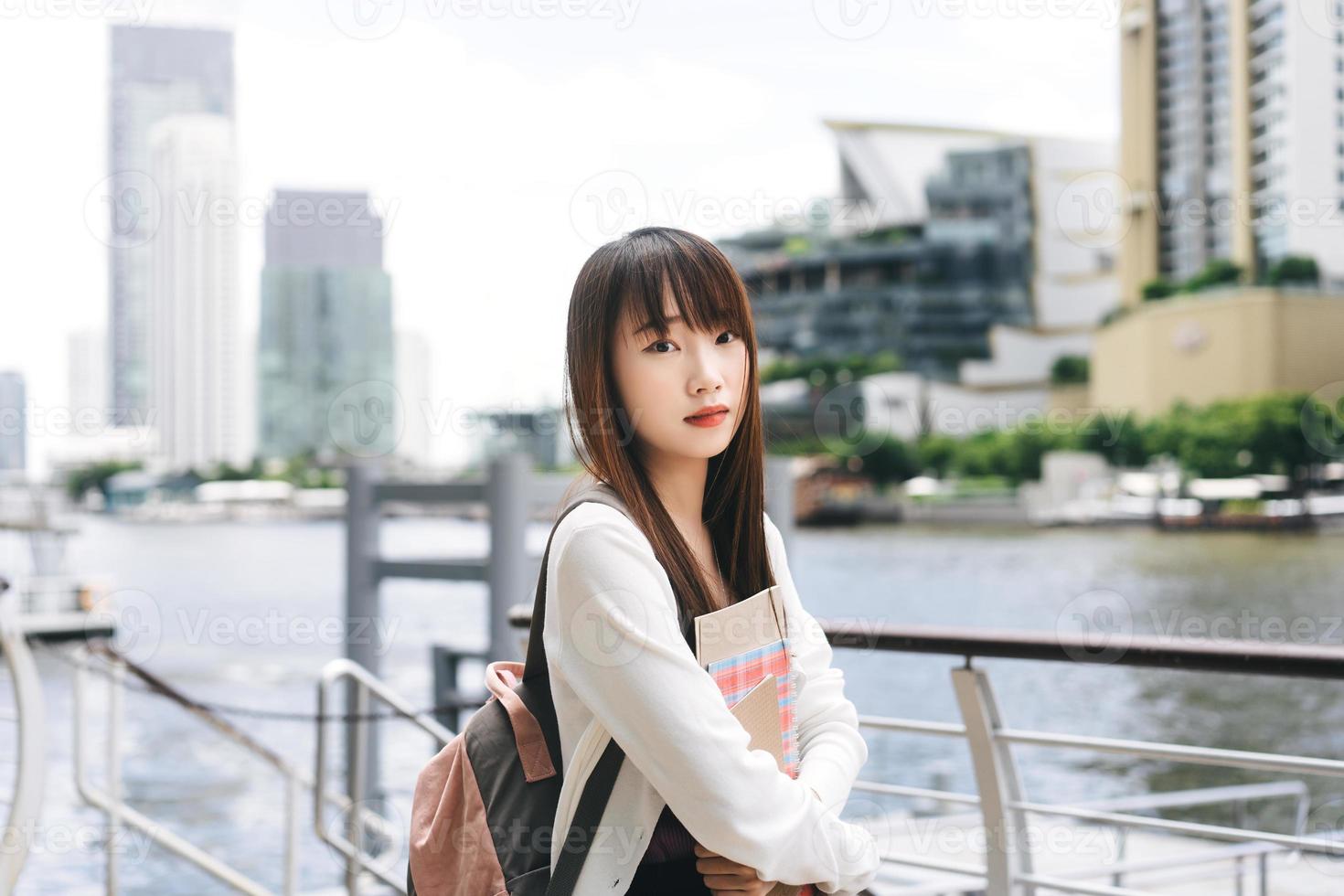 portrait d'une jeune étudiante asiatique adulte avec un ordinateur portable le jour de la ville. photo