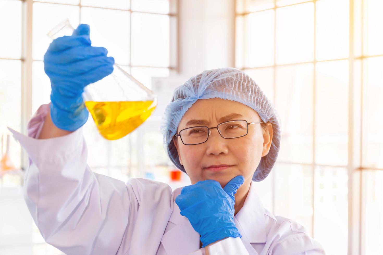 découvrir un remède pour une scientifique asiatique concentrée, tenant un tube à essai et regardant tout en travaillant. photo