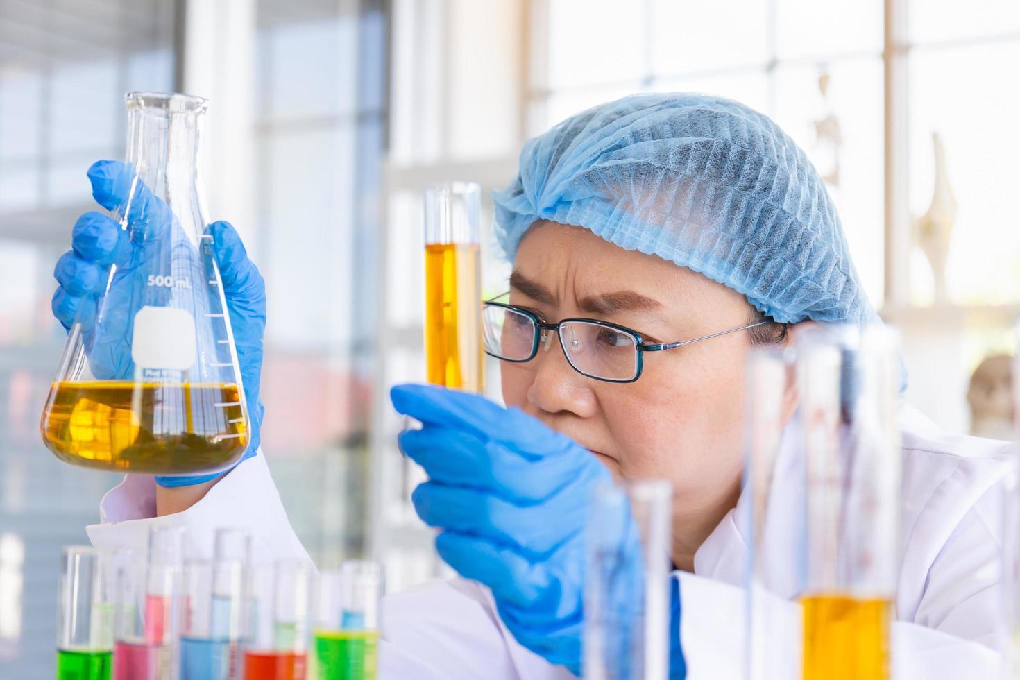 découvrir un remède pour une scientifique asiatique concentrée, tenant un tube à essai et regardant tout en travaillant. photo